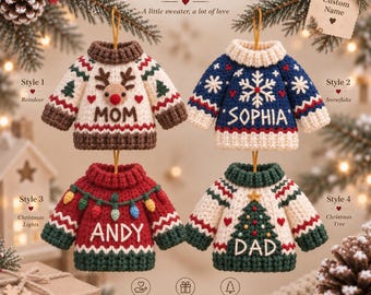 May include: Four personalized sweater ornaments featuring crochet designs: a cream sweater with a reindeer and 'MOM', a blue sweater with a snowflake and 'SOPHIA', a red sweater with Christmas lights and 'ANDY', and a cream sweater with a tree and 'DAD'.