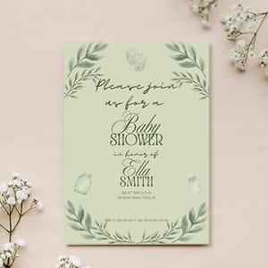 May include: A baby shower invitation with a light green background and a floral design. The invitation includes the text "Please join us for a Baby Shower in honor of Ella Smith."