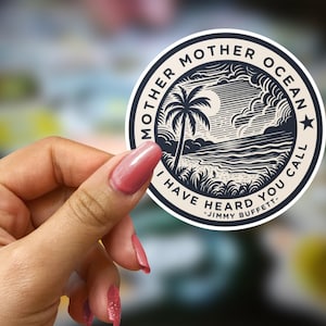 May include: A round sticker with a black and white illustration of a palm tree, ocean, and clouds. The text "MOTHER OCEAN" and "I HAVE HEARD YOU CALL - JIMMY BUFFETT" are printed around the edge of the sticker.