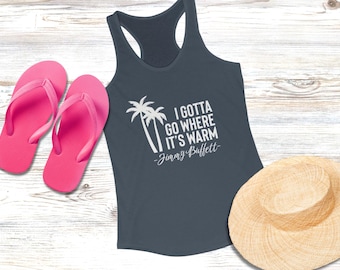Op de afbeelding: Een marineblauwe tanktop met de quote "I Gotta Go Where It's Warm" en een palmboomafbeelding. Roze teenslippers en een strohoed zijn ook in de afbeelding te zien, wat wijst op een strand- of vakantiethema.