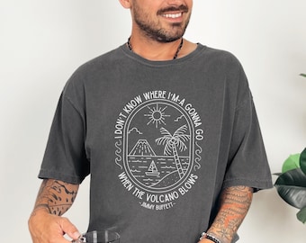 May include: Dark gray t-shirt with a white graphic. The graphic features a volcano, palm tree, sailboat, and the text "I DON'T KNOW WHERE I'M-A GONNA GO WHEN THE VOLCANO BLOWS - JIMMY BUFFETT."