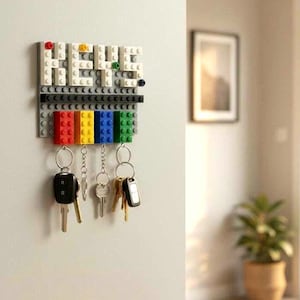 May include: A wall-mounted key holder made from white, black, and gray building blocks. The word "KEYS" is spelled out in white blocks. Below, a row of colorful blocks in red, yellow, blue, and green hold keys on metal rings.