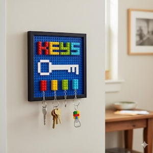 May include: A blue key holder made of toy bricks with the word "KEYS" spelled out in colourful blocks. A white key design is below the word, with keychains hanging from the bottom. The key holder is in a black frame.