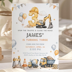 Puede incluir: Una invitación de cumpleaños con temática de construcción. La invitación presenta un gran número 3, una excavadora y el texto "STOP THE TRAFFIC & CLOSE THE ROAD JAMES' IS TURNING THREE". La invitación también incluye la fecha, hora y lugar.