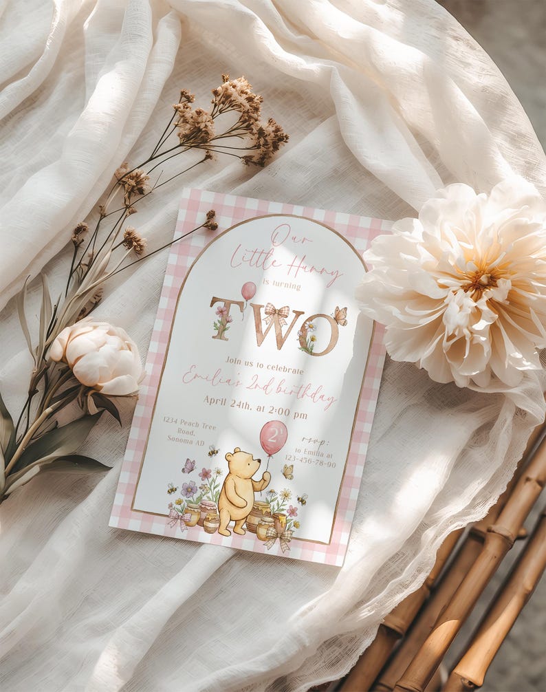 Puede incluir: Una invitaci&oacute;n de cumplea&ntilde;os para un ni&ntilde;o de dos a&ntilde;os, con un borde rosa a cuadros. El texto dice "Our Little Hunny is turning TWO" con detalles florales y mariposas. Incluye una ilustraci&oacute;n de Winnie the Pooh con un globo rosa.