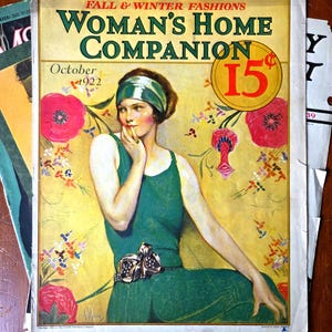 May include: A vintage October 1922 Woman's Home Companion magazine cover featuring an illustration of a person wearing a green sleeveless dress and a matching headband. The background is yellow with red floral accents and the text 15 cents in a circle.