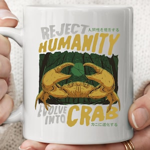 Puede incluir: Taza de cerámica blanca con una ilustración de cangrejo amarillo y las palabras "REJECT HUMANITY EVOLVE INTO CRAB" en gris y amarillo. También se incluye texto en japonés.