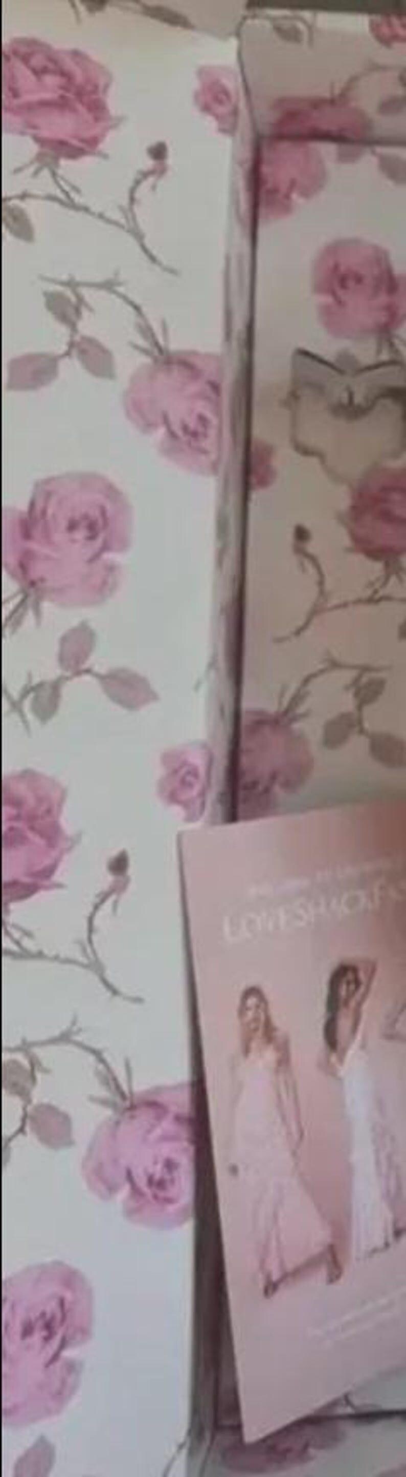 May include: A box and a brochure with a floral rose pattern in pink and white. The brochure features images of women in white dresses. The box is open, revealing the interior.