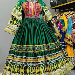 May include: A striking green dress with detailed embroidery and decorative elements. The bodice has a colourful embroidered pattern, and the sleeves and skirt are embellished with gold and white designs. The dress is displayed on a mannequin, highlighting its flowing shape.
