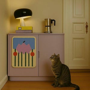 Puede incluir: Una habitaci&oacute;n de estilo moderno con una l&aacute;mpara de hongo negra, una cafetera plateada y un armario con un dise&ntilde;o abstracto colorido. Un gato atigrado est&aacute; sentado en el suelo de madera, mirando hacia arriba. El armario est&aacute; pintado de color lila claro.