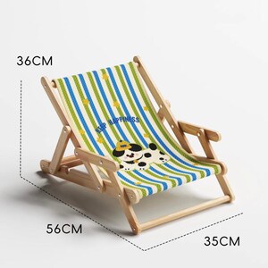 May include: A small wooden deck chair with a striped blue, green, and white fabric seat. The seat features a cartoon dog design and the words "KEEP HAPPINESS". The chair measures 22 inches long, 14 inches wide, and 13 inches high.