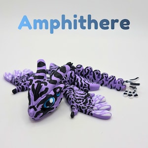 May include: A 3D printed articulated amphithere figure featuring a purple and black tiger-stripe pattern. The creature has large blue eyes, wing-like appendages, and a segmented tail ending in a white and black clawed tip. The text Amphithere is visible.