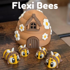 May include: A brown beehive-shaped ornament with a small house and door, adorned with white and yellow flowers. Four yellow and brown bee figurines are in front of the beehive. The text "Flexi Bees" is at the top.