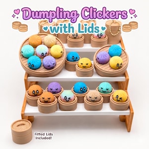 May include: A collection of Dumpling Clickers with Lids featuring colorful, round, smiling dumpling characters in individual tan bamboo-style steamer baskets arranged on a white tiered display stand with text reading Dumpling Clickers with Lids.