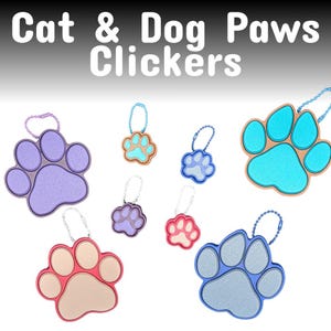 May include: Colorful cat and dog paw-shaped clickers in various colors, including purple, blue, and pink. Each clicker has a metal chain and a ring for attachment. The text "Cat & Dog Paws Clickers" is at the top of the image.