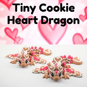 May include: Two brown and white cookie dragons with heart-shaped details and pink accents. The text "Tiny Cookie Heart Dragon" is displayed above the cookies against a background of pink hearts.