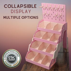 May include: A pink collapsible display stand featuring four tiered storage bins and a top pegboard section with multiple hooks. The text COLLAPSIBLE DISPLAY MULTIPLE OPTIONS is visible. A circular logo reads CERTIFIED RK-DESIGN LICENSEE.