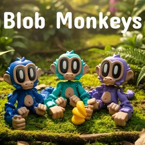 May include: Three colorful Blob Monkeys toys in blue, teal, and purple, sitting on moss. Each monkey has large, oval eyes and a neutral expression. The text "Blob Monkeys" is displayed above the toys.