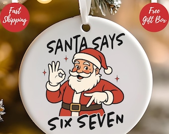 May include: A white ceramic Christmas ornament with a cartoon Santa Claus illustration. The ornament features the text "SANTA SAYS SIX SEVEN" in black lettering. Santa is wearing a red suit and hat, and is giving the "okay" sign.