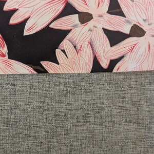 May include: A textile composition featuring a top section with a black background adorned with light pink floral patterns and a bottom section consisting of a solid grey fabric with a visible woven texture and cross-hatched pattern.