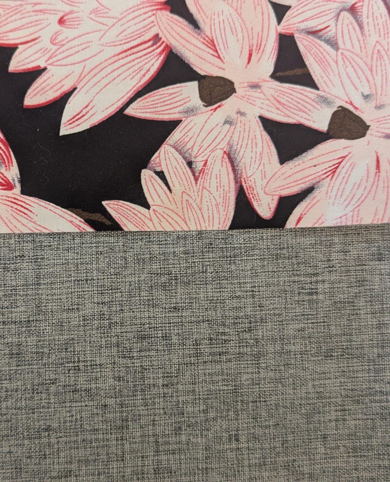 May include: A textile composition featuring a top section with a black background adorned with light pink floral patterns and a bottom section consisting of a solid grey fabric with a visible woven texture and cross-hatched pattern.