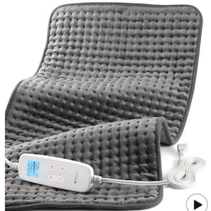 May include: A gray, quilted heating pad with a digital control panel. The pad is rectangular and made of a soft, plush material. The control panel displays temperature settings and has buttons for adjusting the heat.