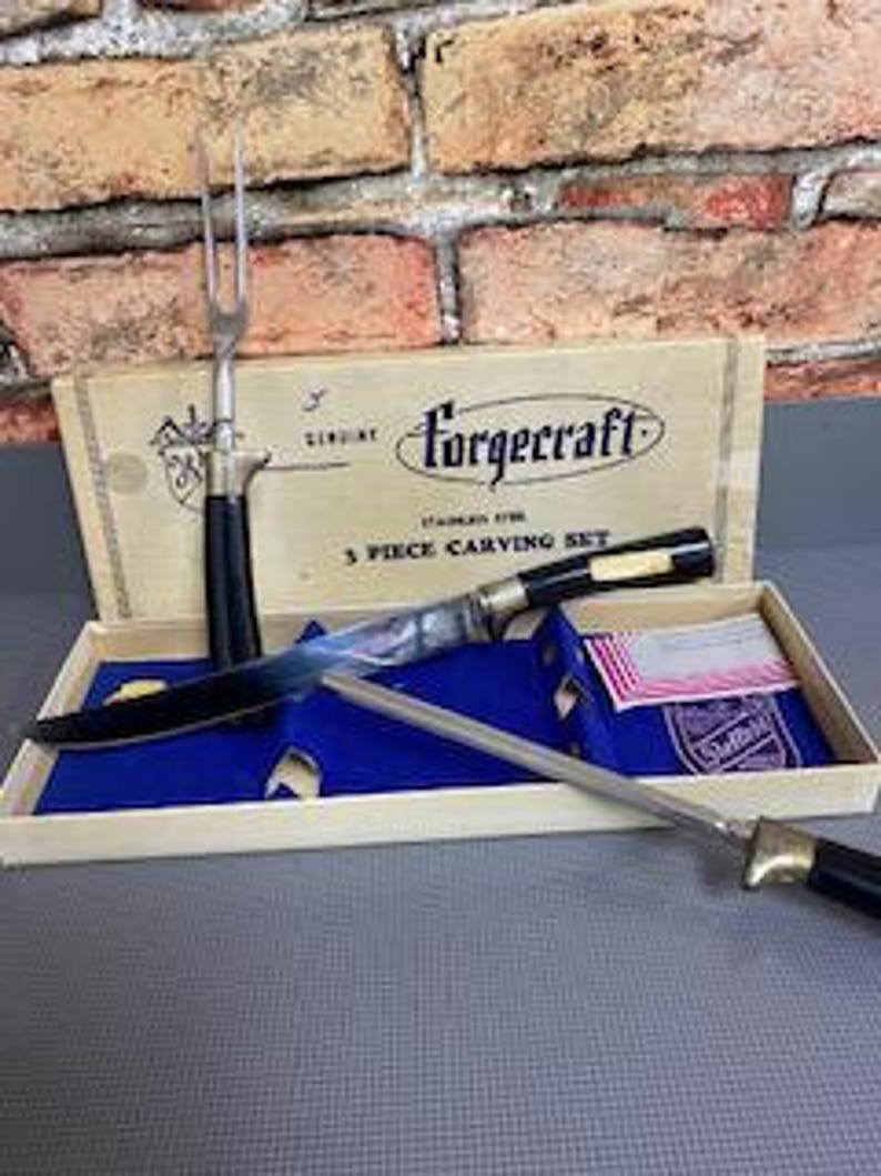 May include: A vintage Forgcraft 3-piece carving set in a box. The set includes a carving knife, a carving fork, and a sharpening steel. The knife and fork have black handles and silver blades. The box is beige with black text.