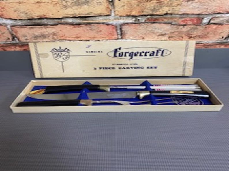 May include: A vintage Forgcraft 3-piece carving set in its original box. The set includes a carving knife, a carving fork, and a sharpening steel. The handles are black, and the blades are stainless steel. The box is beige with black text.