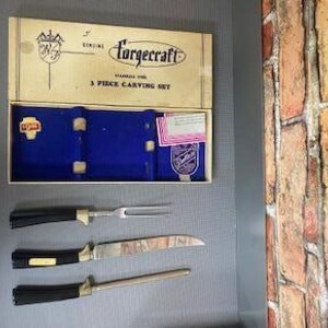 May include: Vintage Forgecraft 3-piece carving set. The set includes a carving knife, fork, and sharpening steel. The blades are stainless steel with black handles and gold accents. The set comes in its original box with the brand name and logo.