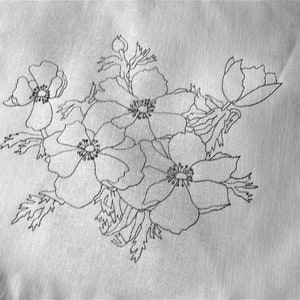May include: A black and white embroidered design of a bouquet of flowers on a white fabric background.