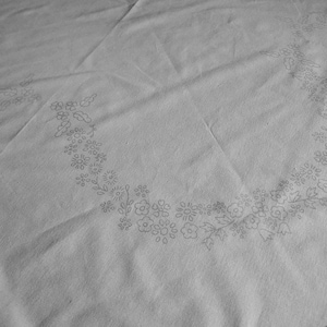 Peut inclure: Une nappe blanche avec un délicat motif de broderie florale autour du bord. La nappe a une bordure en dentelle.
