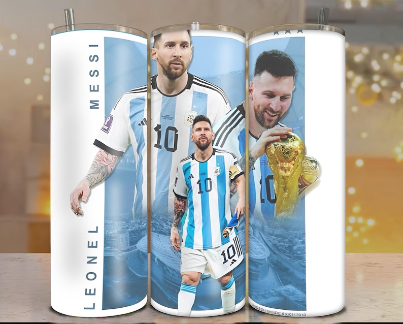 May include: A white stainless steel tumbler featuring images of Lionel Messi in his Argentina soccer uniform. The tumbler has a silver straw and the name "LEONEL MESSI" printed vertically. The design includes the number 10 and a gold trophy.