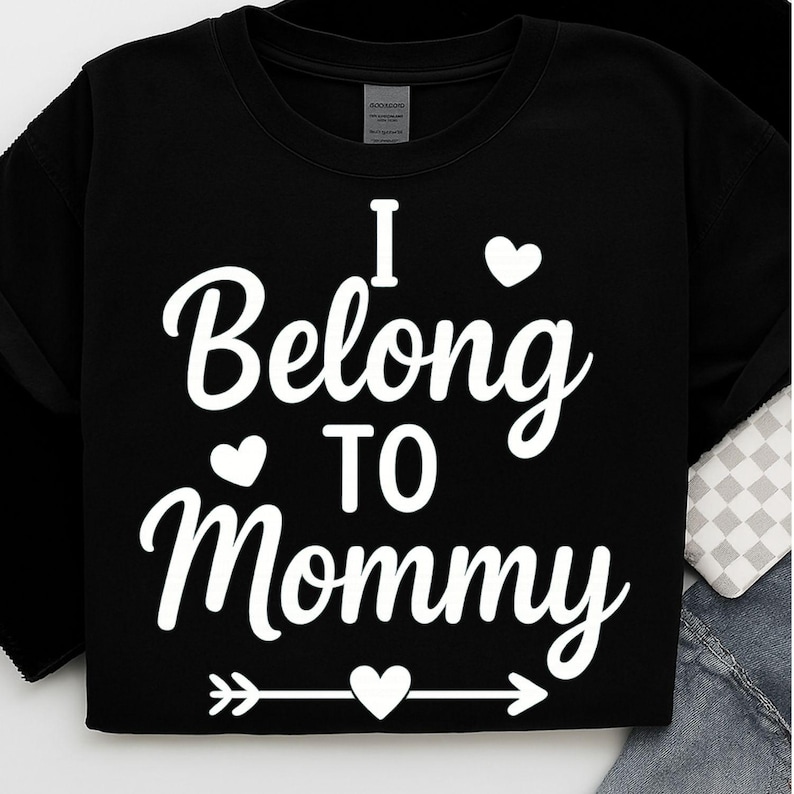 May include: Black sweatshirt with the white text "I Belong To Mommy" in a script font. The design includes heart shapes and an arrow. The sweatshirt is a casual garment.