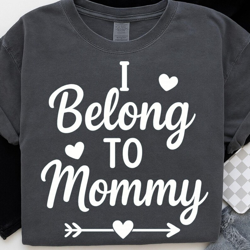 May include: Dark gray t-shirt with the white text "I Belong to Mommy" in a script font. The design includes heart shapes and an arrow. The shirt is a crew neck style.