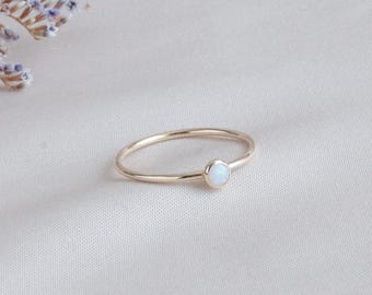 May include: A delicate gold ring with a small white opal gemstone.