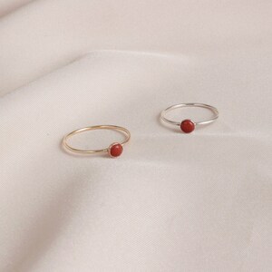Puede incluir: Dos anillos simples con una piedra preciosa roja. Un anillo es de oro y el otro es de plata.