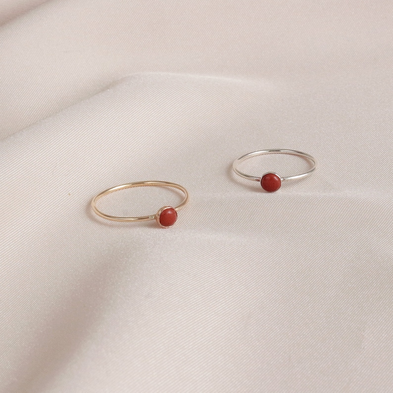 Puede incluir: Dos anillos simples con una piedra preciosa roja. Un anillo es de oro y el otro es de plata.