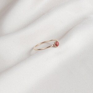 Puede incluir: Un delicado anillo de oro con una sola piedra preciosa redonda de color marr&oacute;n rojizo.