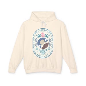 May include: Cream-colored hooded sweatshirt with a circular graphic. The graphic features a blue and brown design with the text "#0009" at the top and "KANTO" at the bottom. The design includes waves, coral, and other abstract shapes.
