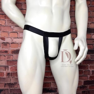Puede incluir: Un suspensorio negro con una cintura elástica ancha y un diseño de bolsa frontal abierta. La prenda incluye el texto del logotipo DV DARK VELVET LEATHER STORE impreso en un color claro en la parte inferior derecha de la tela.