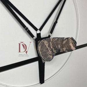 May include: Black harness with adjustable straps and a patterned pouch. The pouch features a beige and brown snakeskin design. The harness is suspended against a white background.