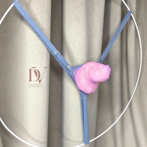 Puede incluir: Un tanga azul claro con un inserto de felpa rosa. El tanga presenta tirantes ajustables y un dise&ntilde;o delicado. La imagen est&aacute; sobre un fondo neutro, resaltando el color y la forma de la lencer&iacute;a.