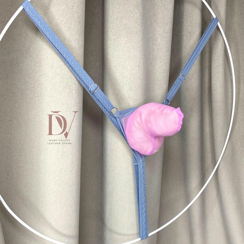 Puede incluir: Un tanga azul claro con un inserto de felpa rosa. El tanga presenta tirantes ajustables y un dise&ntilde;o delicado. La imagen est&aacute; sobre un fondo neutro, resaltando el color y la forma de la lencer&iacute;a.
