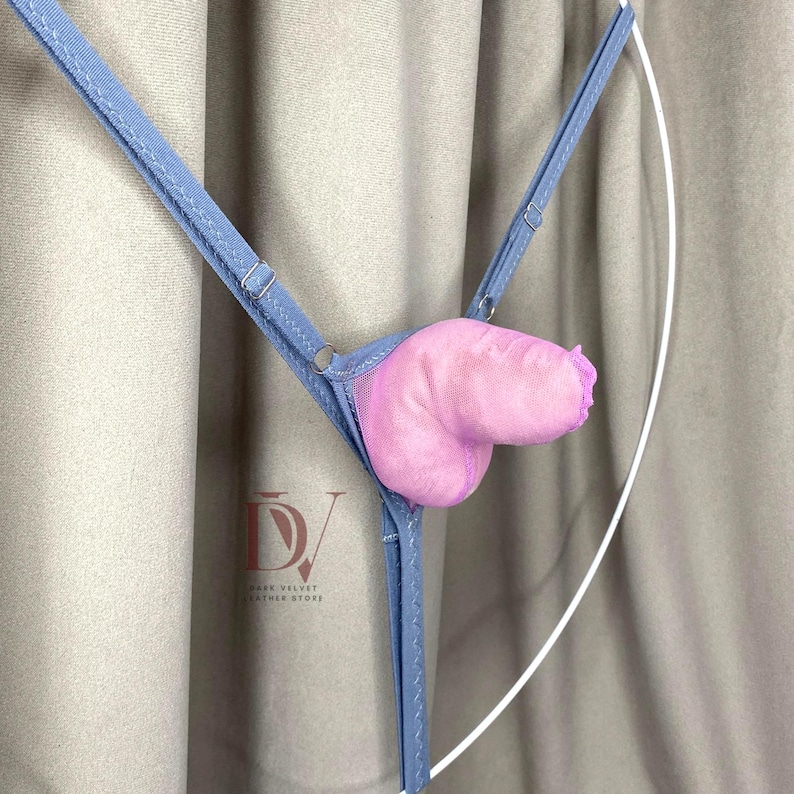 Puede incluir: Un tanga azul claro con un dise&ntilde;o anat&oacute;mico rosa y afelpado. El tanga presenta tirantes ajustables y un panel de malla. El producto se muestra sobre un fondo neutro.