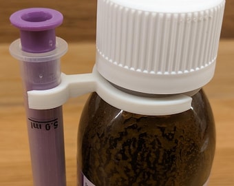 May include: A brown glass medicine bottle with a white screw cap and a white plastic adapter holding a purple oral syringe. The bottle features a label with dosage instructions and text including "For the relief of fever after vaccination".