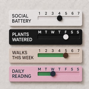 May include: Four rectangular tracking boards with sliding markers. The white board reads SOCIAL BATTERY with numbers 1-7. The black board reads PLANTS WATERED with M-S. The beige board reads WALKS THIS WEEK with 1-7. The pink board reads DAILY READING with M-S.