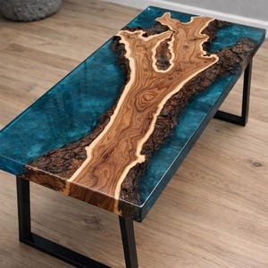 May include: A rectangular coffee table with a unique design. The table features a wooden centerpiece with a natural, organic shape, encased in a clear, turquoise-colored resin. It rests on a black metal frame, creating a modern aesthetic.