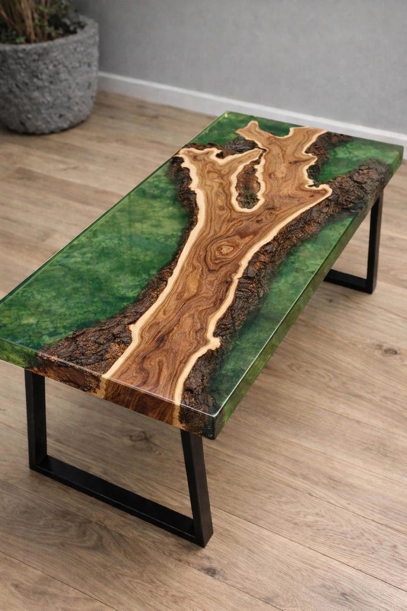 May include: A rectangular coffee table with a unique design. The table features a wooden centerpiece with a natural tree-like pattern, encased in a clear green resin. It rests on black metal legs, creating a modern and artistic aesthetic.
