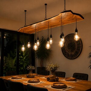 May include: A live edge wooden slab pendant light fixture suspended by black chains, featuring ten hanging Edison-style light bulbs with visible filaments. The fixture is positioned above a long wooden dining table with place settings.