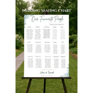 May include: A white wedding seating chart on a black easel, with the text "Wedding Seating Chart" and "Our Favourite People". The chart lists names under numbers one through fifteen, with the names "John & Sarah" and the date "JAN 17 2026" at the bottom.